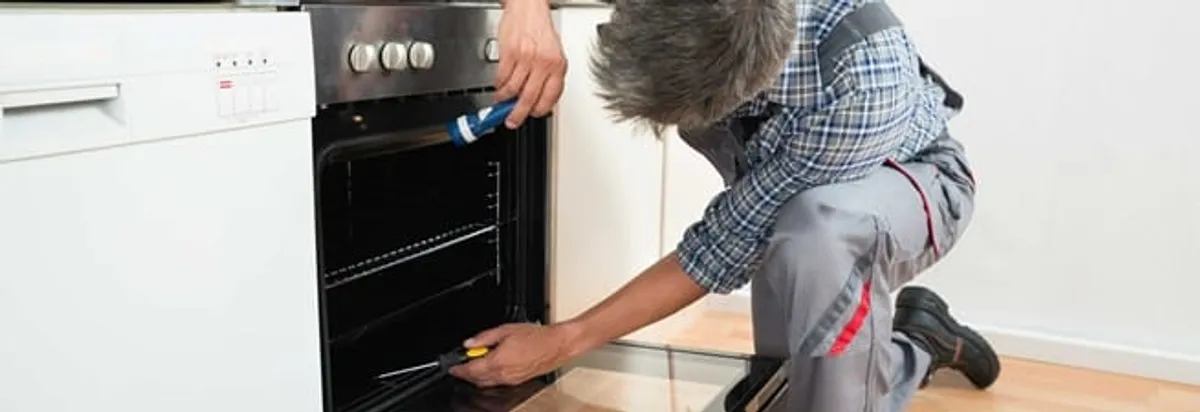Oven repair technician inspecting and servicing an electric oven in Reno, NV