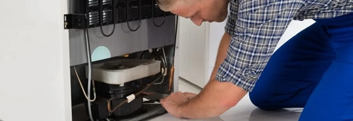 Refrigerator repair technician servicing the compressor and condenser area in Reno, NV