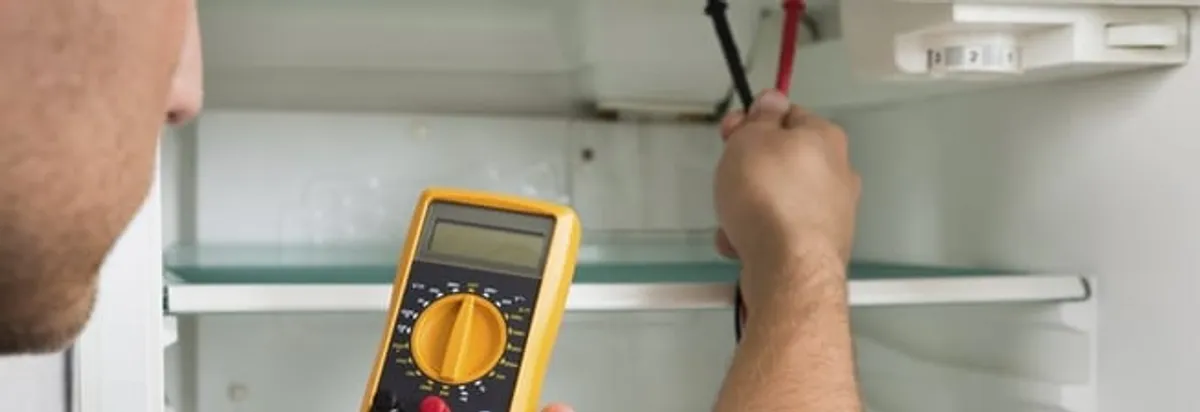 Refrigerator repair technician testing electrical components with a multimeter in Reno, NV